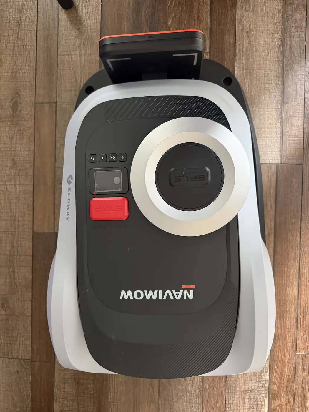 Top-down view of the Segway Navimow i215 LiDAR seated on its charging station, showing the EFLS dome, red STOP button, status display, four navigation keys, Segway branding and the i215 LiDAR model designation moulded into the shell