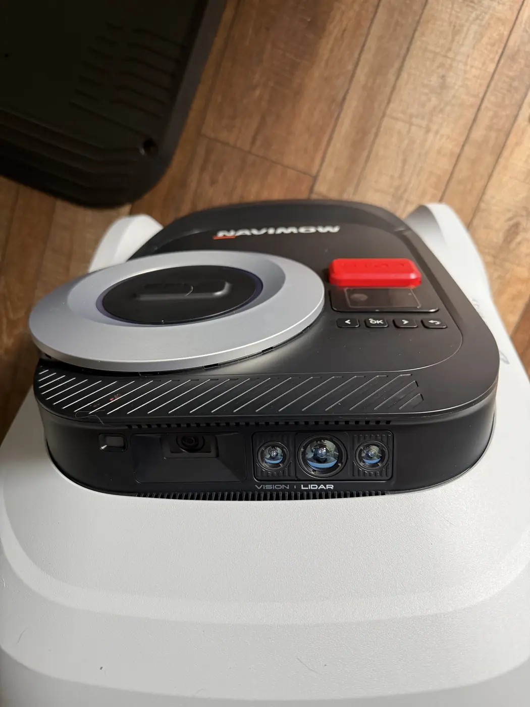 Close-up of the Navimow i215 LiDAR front sensor module showing three LiDAR apertures and a camera housing beneath a panel printed VISION and LIDAR, with the EFLS dome, red STOP button, status display and four navigation keys visible above