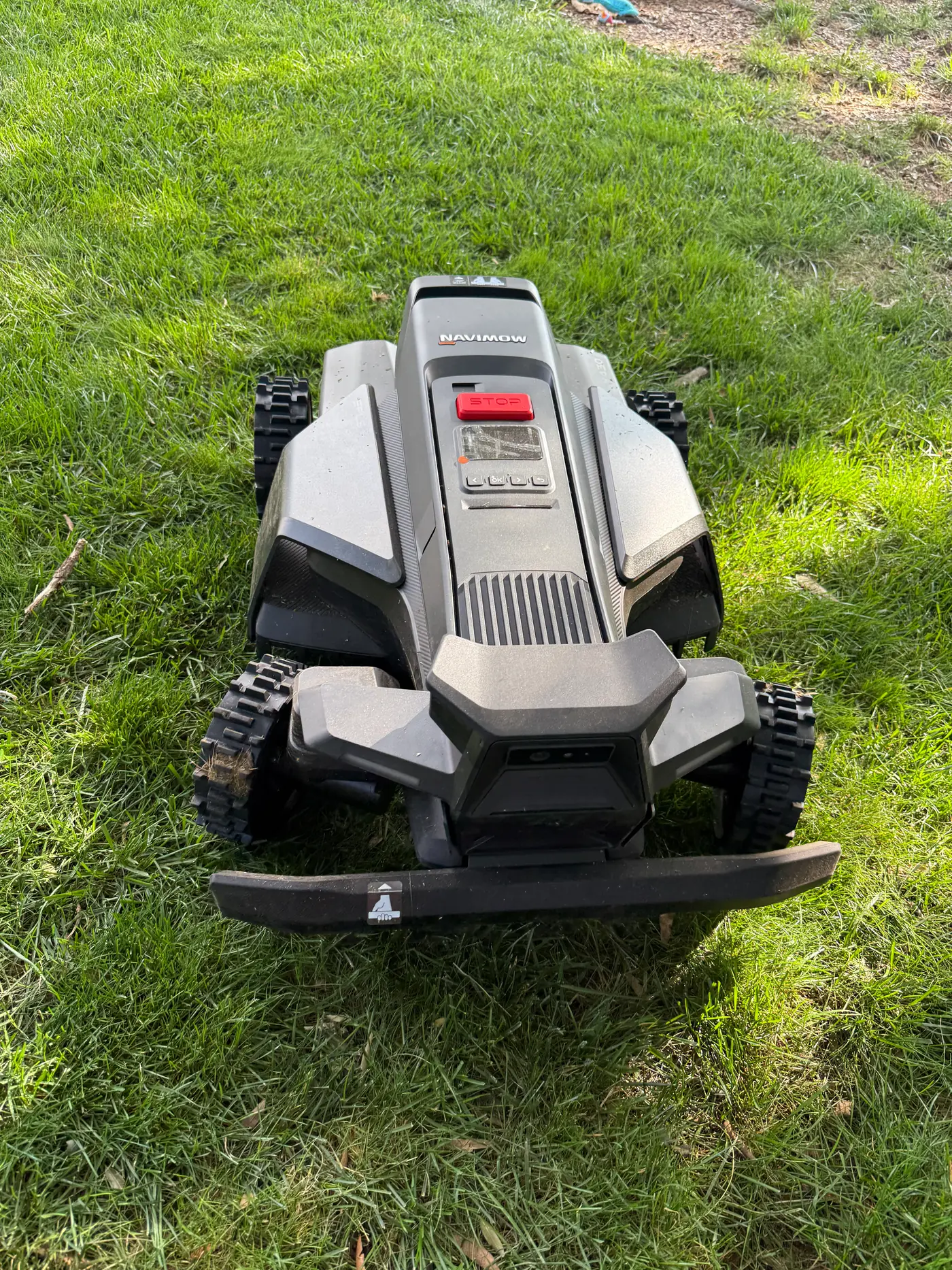 Front view of the Segway Navimow X430 on grass — close detail of the front rubber bumper, sensor housing, and aggressive-tread Xero-Turn front wheels