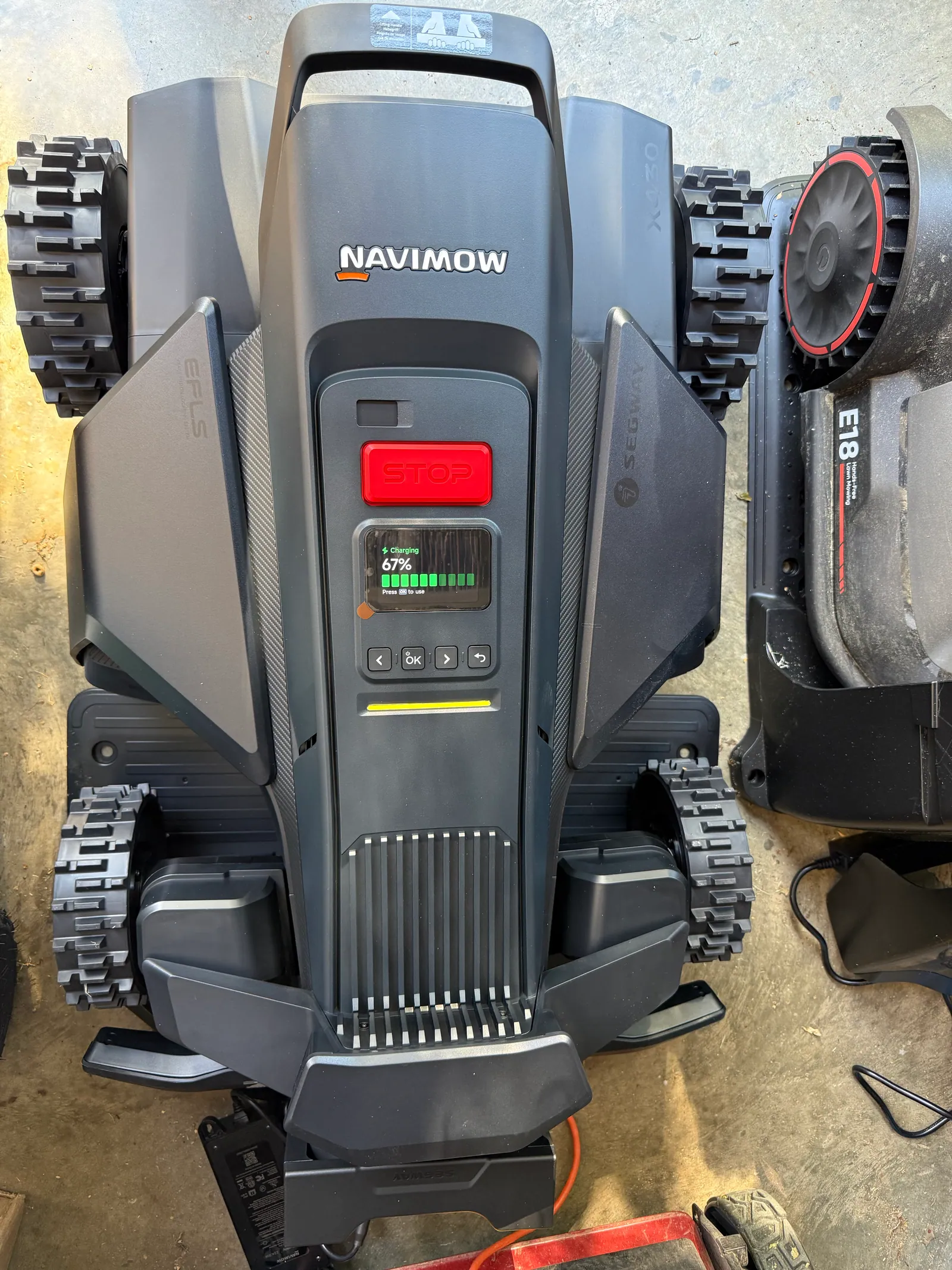 Top-down view of the Segway Navimow X430 showing the control panel, START button, EFLS 3.0 status LEDs, and the four aggressive-tread 4WD Xero-Turn wheels — hardware shared with the X450 flagship
