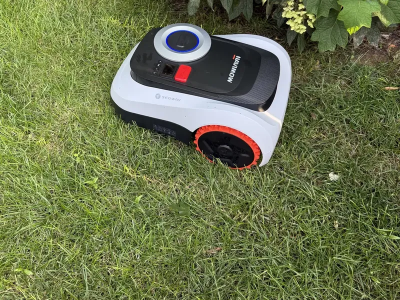 Segway Navimow i215 LiDAR robotic lawn mower cutting alongside a shrub bed